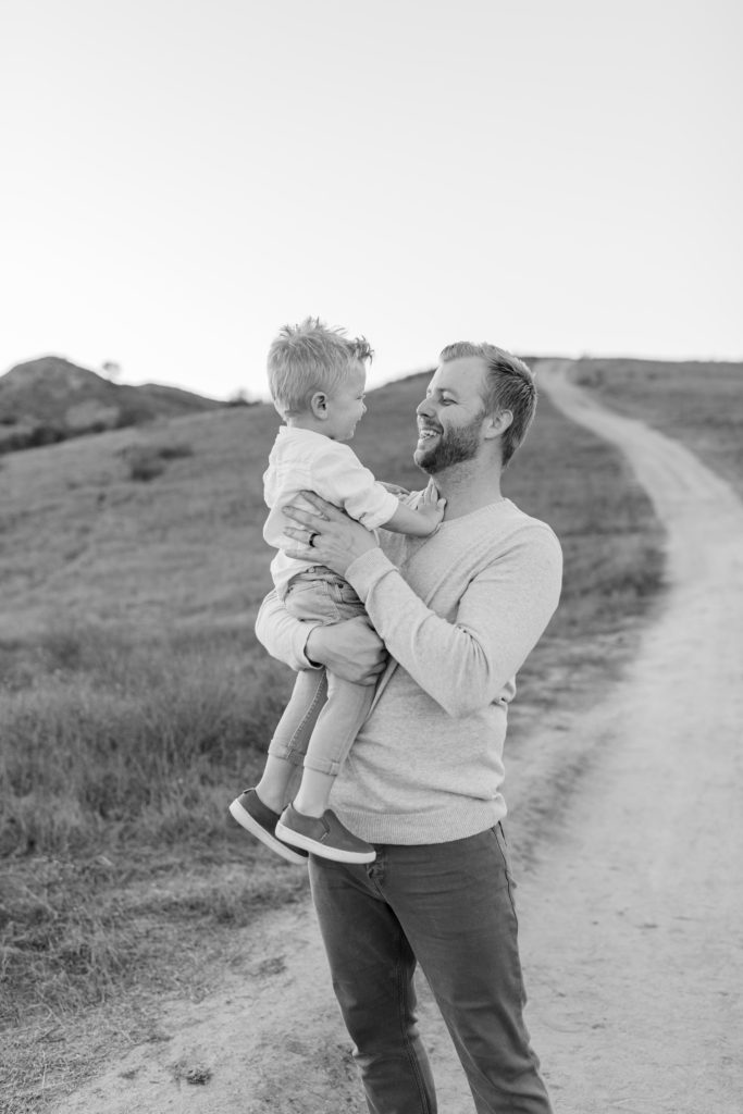 Katelyn Jones A Touch of Pink Blog Family Photoshoot with Reshma Photography in Southern California Orange County. Father Alex is Smiling for photo with son Dane in black and white photo